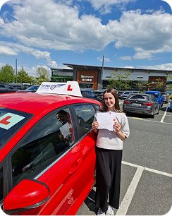Young woman smiling proudly outdoors on a bright day, holding a certificate, excited expression (1)